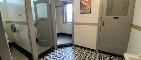 Un baño de hotel con baldosas estampadas en el suelo, un inodoro, un lavabo y una ducha.