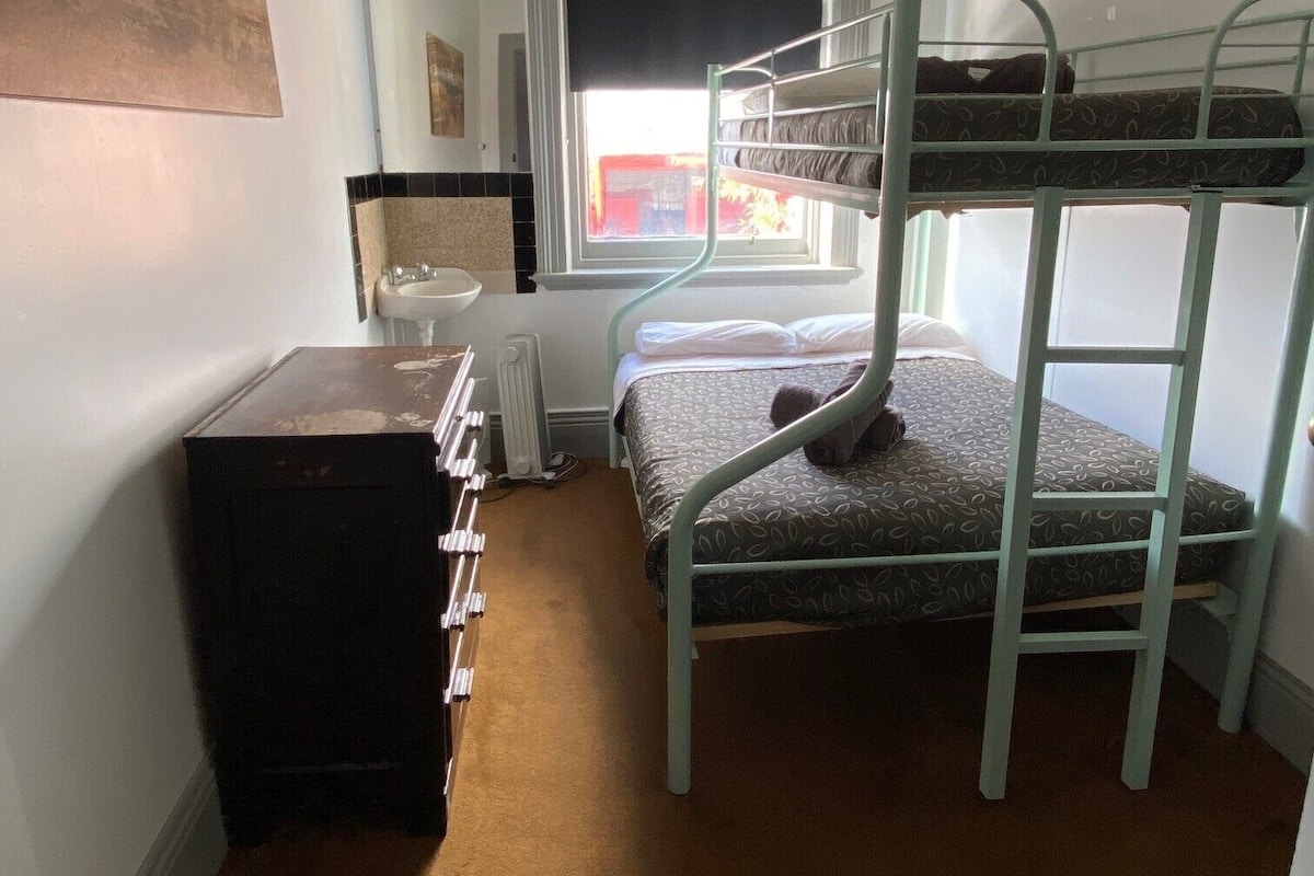 Habitación con literas, ventana, radiador y cómoda.