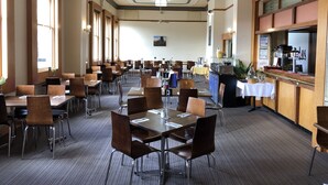 A spacious dining area with multiple tables and chairs, a bar counter, and a ceiling fan. - Royal Hotel (Horsham)