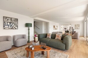 A modern living room with a green sofa, two grey armchairs, a wooden coffee table, and a patterned rug. - Villa TourterelleLuxurious villa with breathtaking sea views! (Roquebrune-sur-Argens)