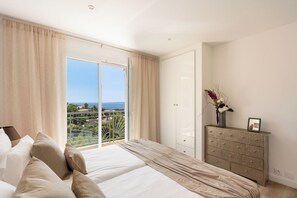 Ein Schlafzimmer mit Bett, Kommode und Meerblick.