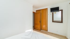 A bedroom with a bed, white towels, a television, and wooden doors.