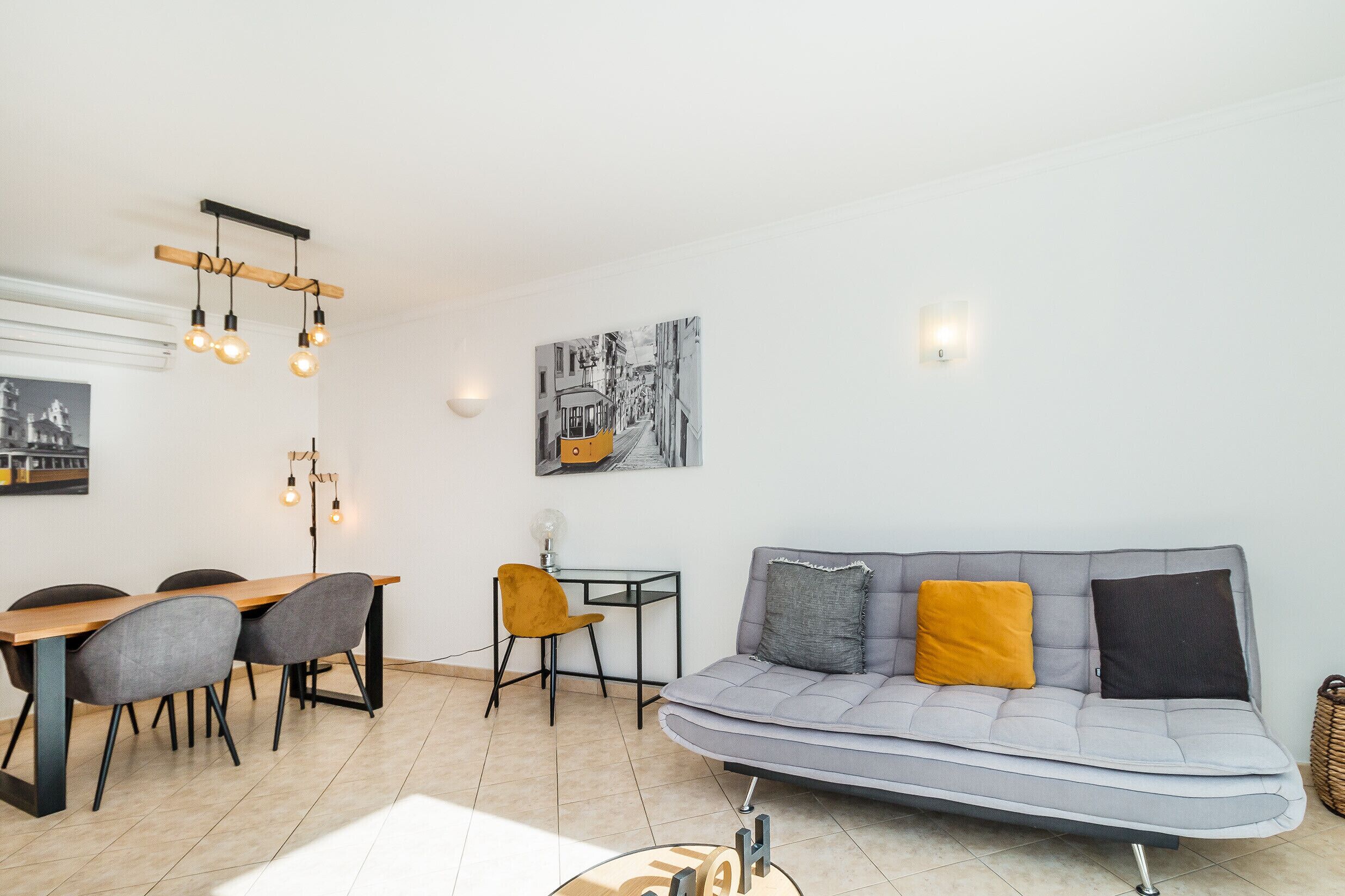 Un salon moderne comprenant un canapé, une table à manger, des chaises et un luminaire suspendu.
