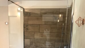 A glass-enclosed shower with a wooden wall and a white floor. - Bastide Campagne Canal (Cucuron)