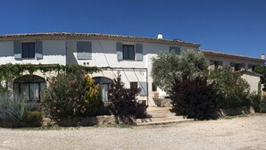 A two-story house with a white facade, multiple windows with shutters, and a stone staircase leading to the entrance. - Bastide Campagne Canal (Cucuron)