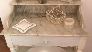 A white marble desk with shelves, a basket, a candle, and a decorative item. - Bastide Campagne Canal (Cucuron)