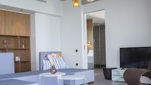 Una sala de estar moderna con un sofá, un televisor y una mesa de centro de vidrio.