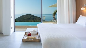 Un dormitorio con una cama grande, una bandeja con alimentos para el desayuno y vistas a un paisaje costero.