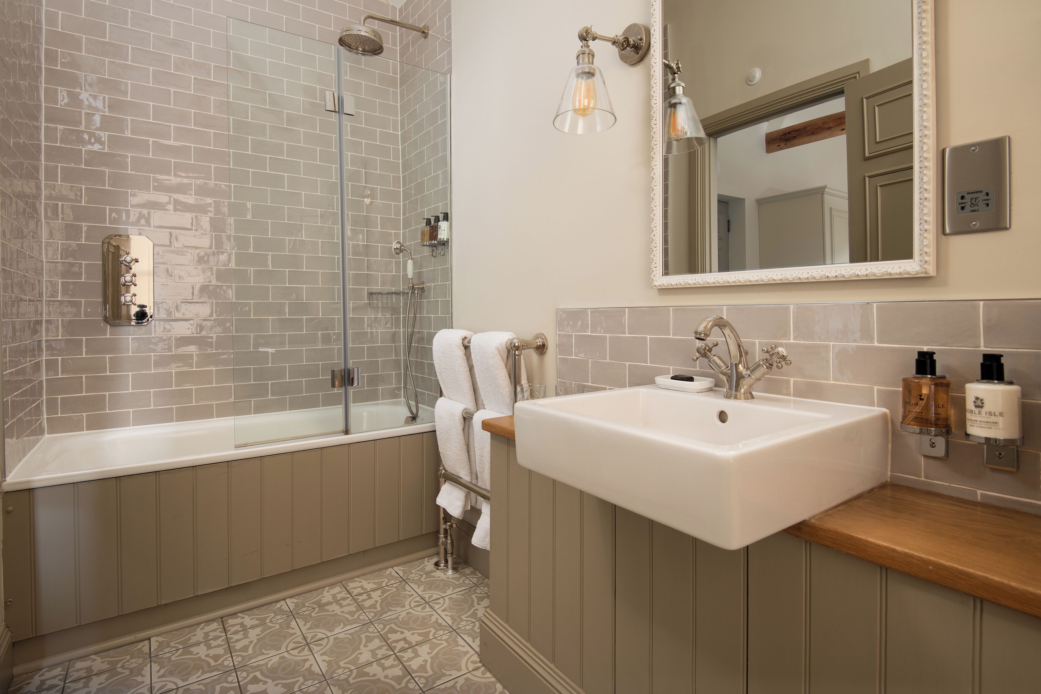 A modern bathroom with a glass shower, a large sink, and a mirror above it.