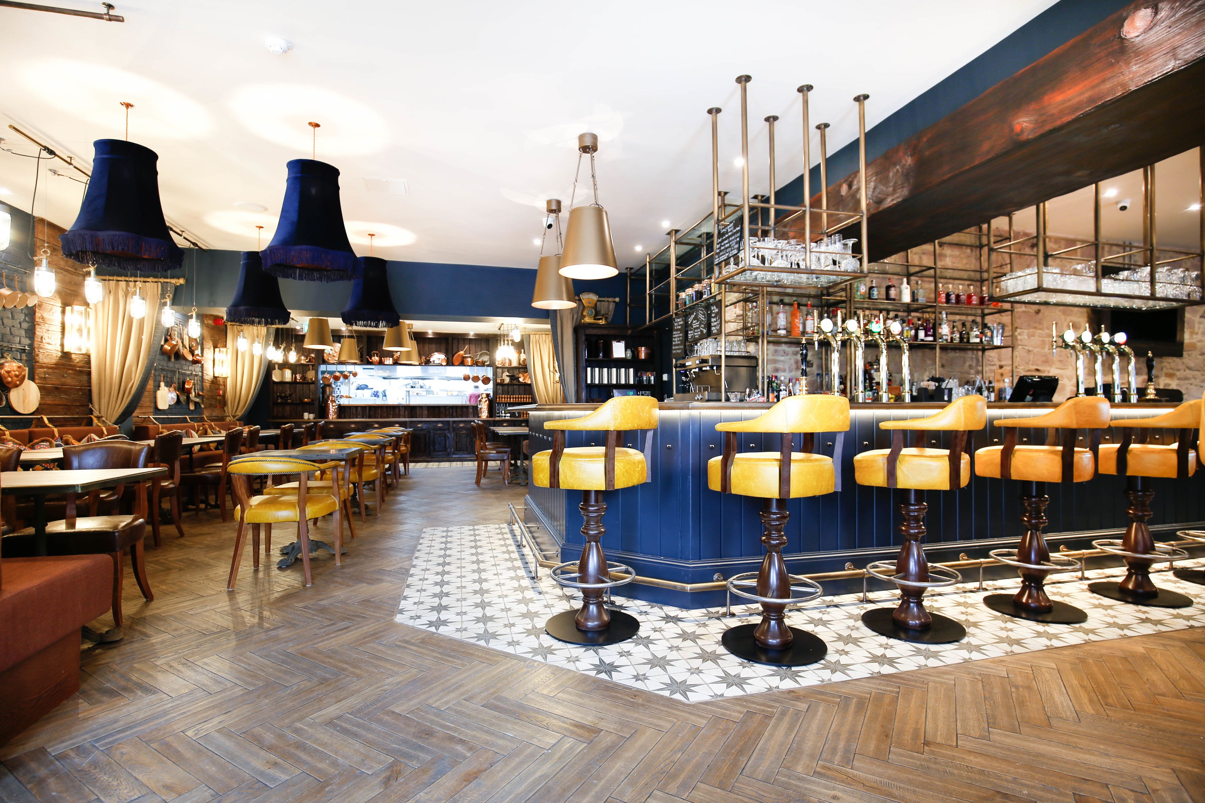 A bar area with multiple stools, a bar counter, and a variety of bottles on shelves.