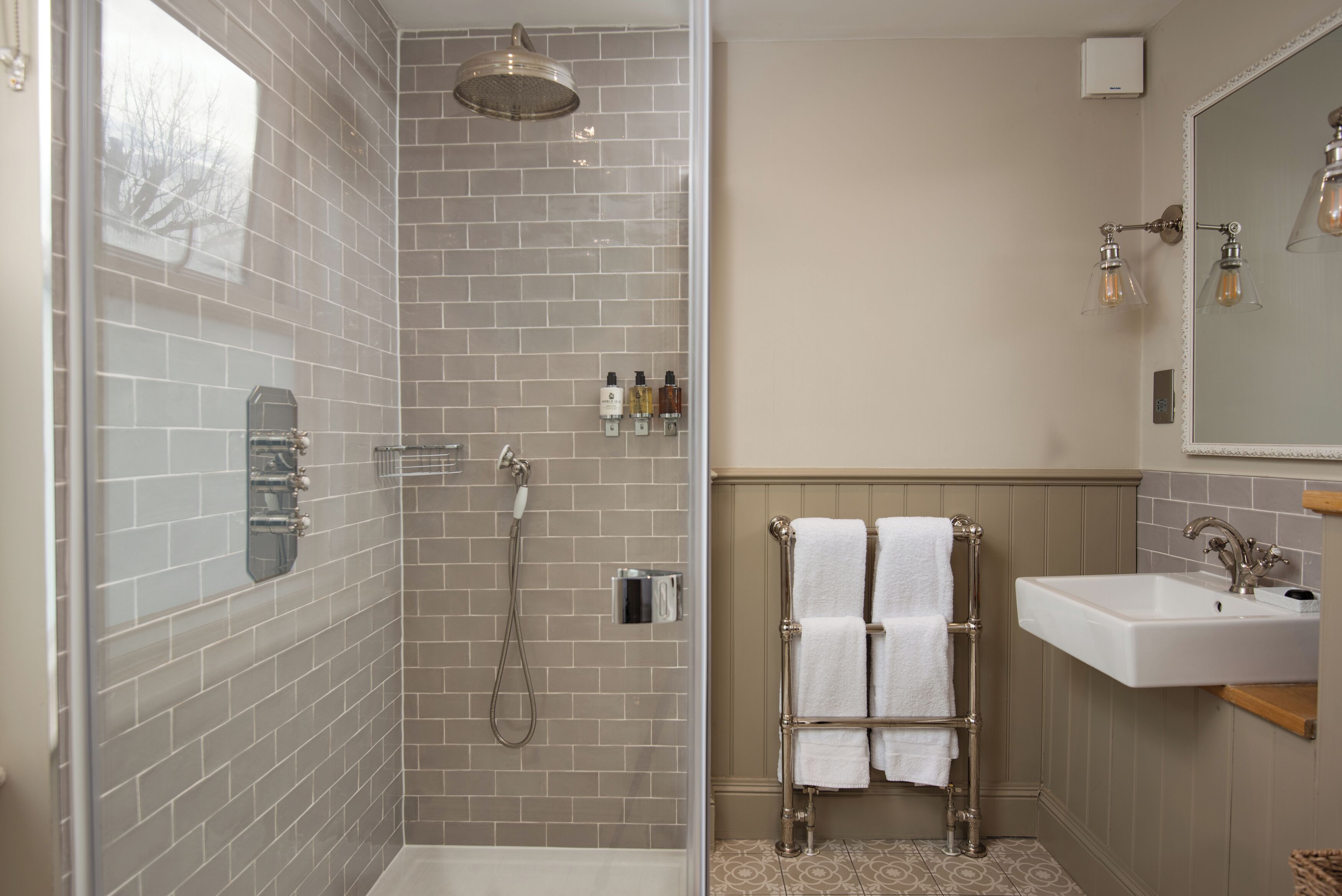 A bathroom with a shower, a sink, and a towel rack.
