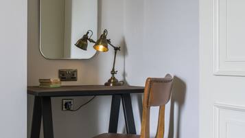 Un escritorio con una silla, una lámpara y un espejo.