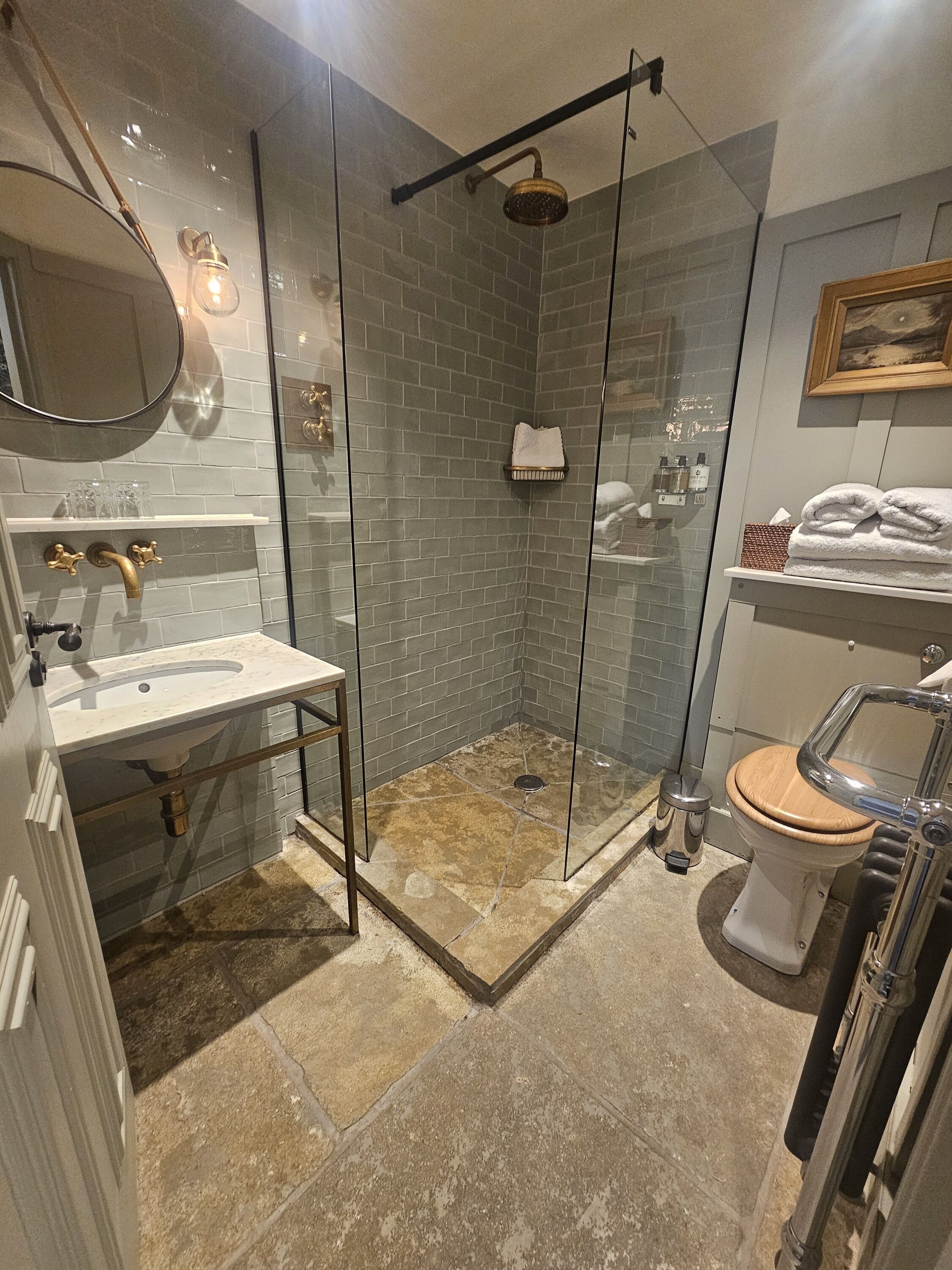A modern bathroom with a glass-enclosed shower, a white sink, and a wooden toilet.