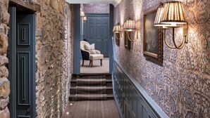 A hallway with stone walls, a blue door, and a chair. There are steps leading to a door with a blue frame. - Beadnell Towers Hotel (Chathill)