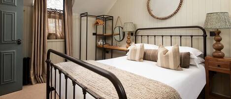 A bedroom with a bed, bedside tables, a mirror, and a door.