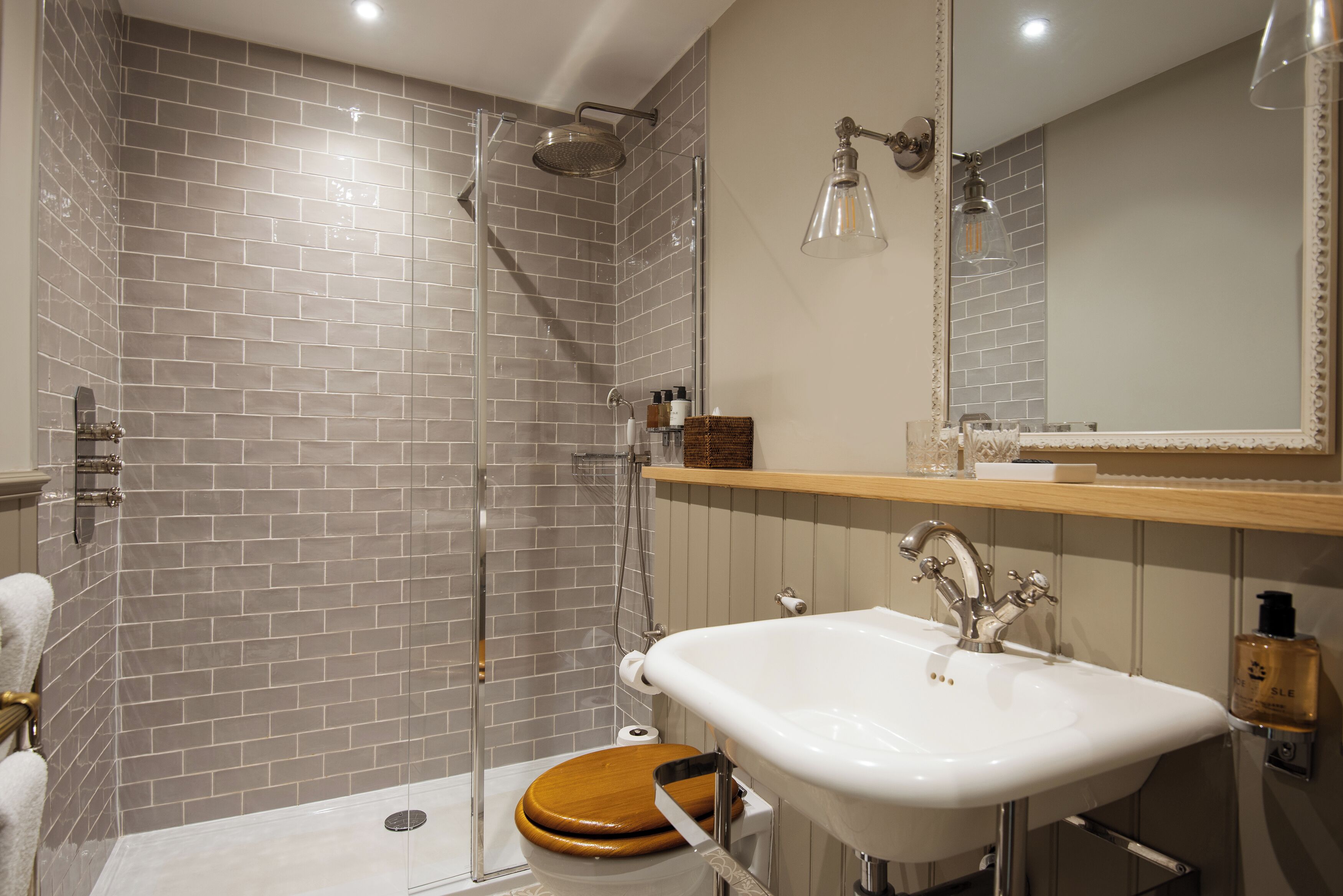 A bathroom with a shower, toilet, sink, and mirror.