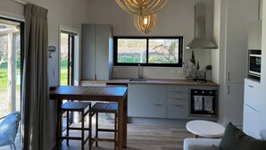 Eine moderne Küche mit großem Fenster, einem Holztisch und Barhocker.
