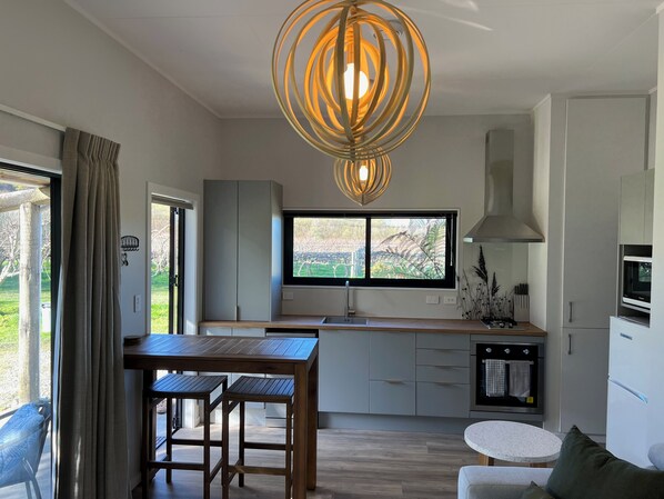 Una cocina moderna con un ventanal grande, una mesa de madera y taburetes de bar.