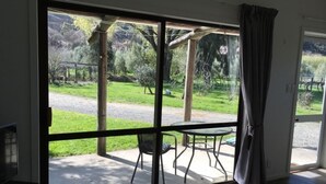 Ein Zimmer mit einer Schiebetür zum Patio, auf dem ein Tisch und Stühle stehen.