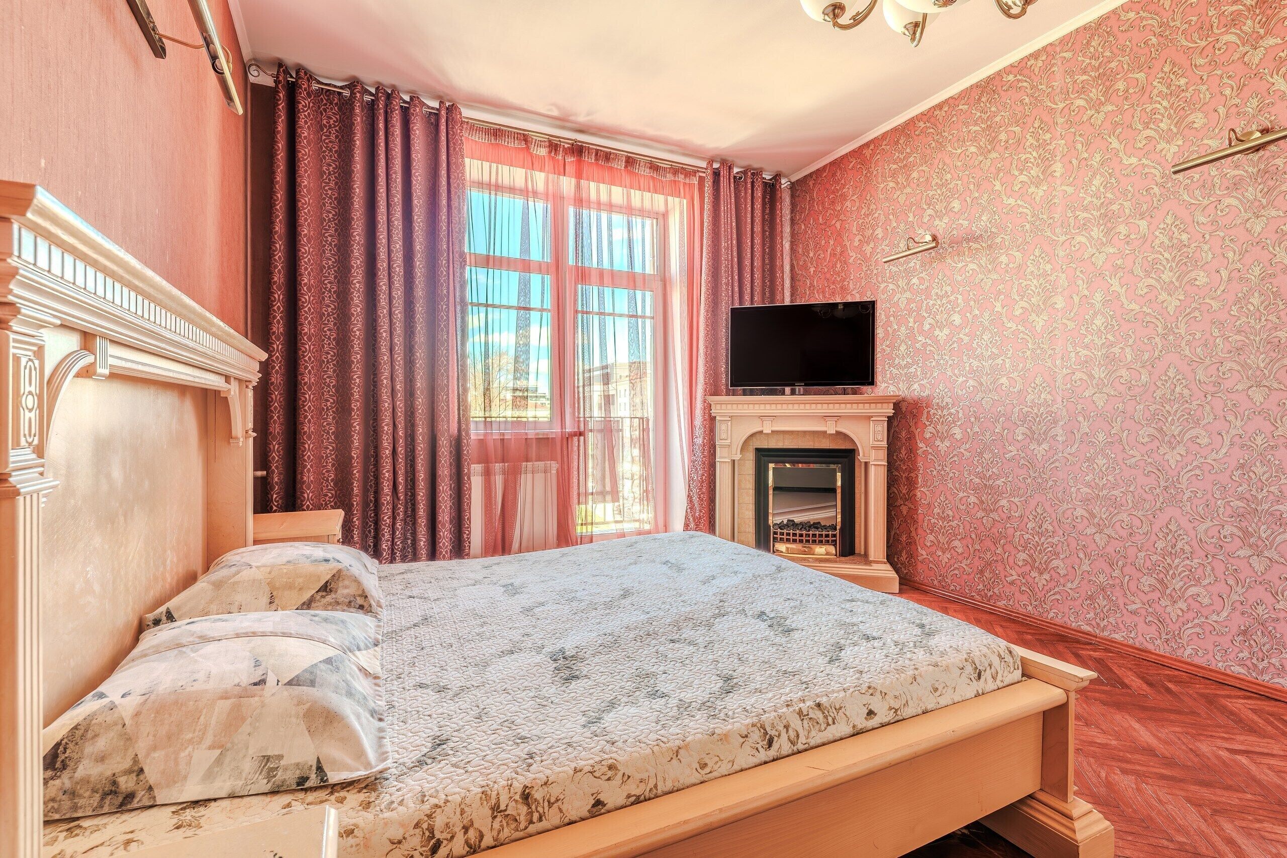 A bedroom with a bed, a television, and a fireplace.