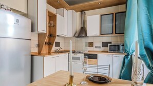 Une cuisine moderne avec des meubles blancs, un réfrigérateur en acier inoxydable, un four à micro-ondes et un plan de travail en bois.