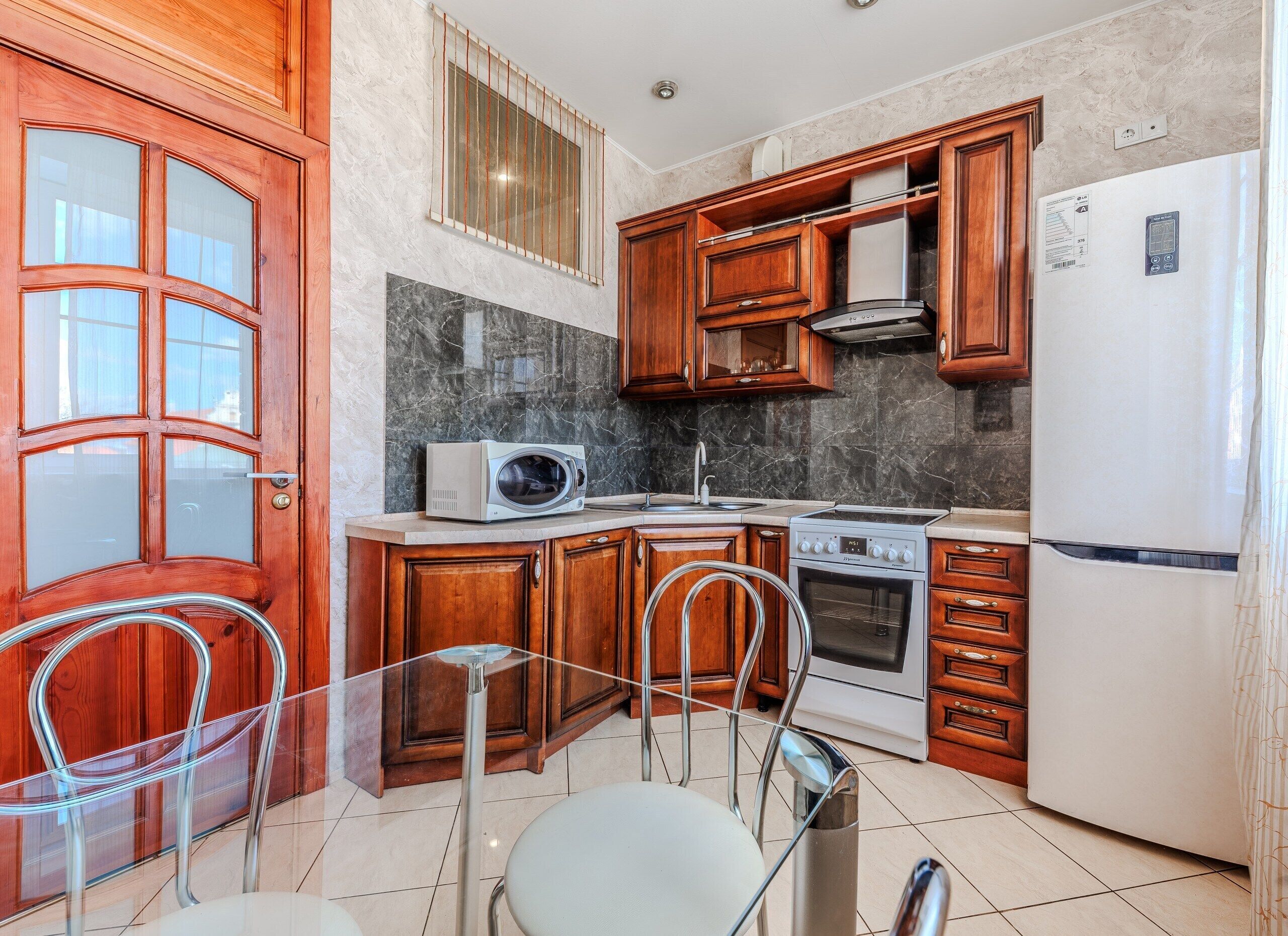 A kitchen with wooden cabinets, a microwave, stove, and refrigerator.