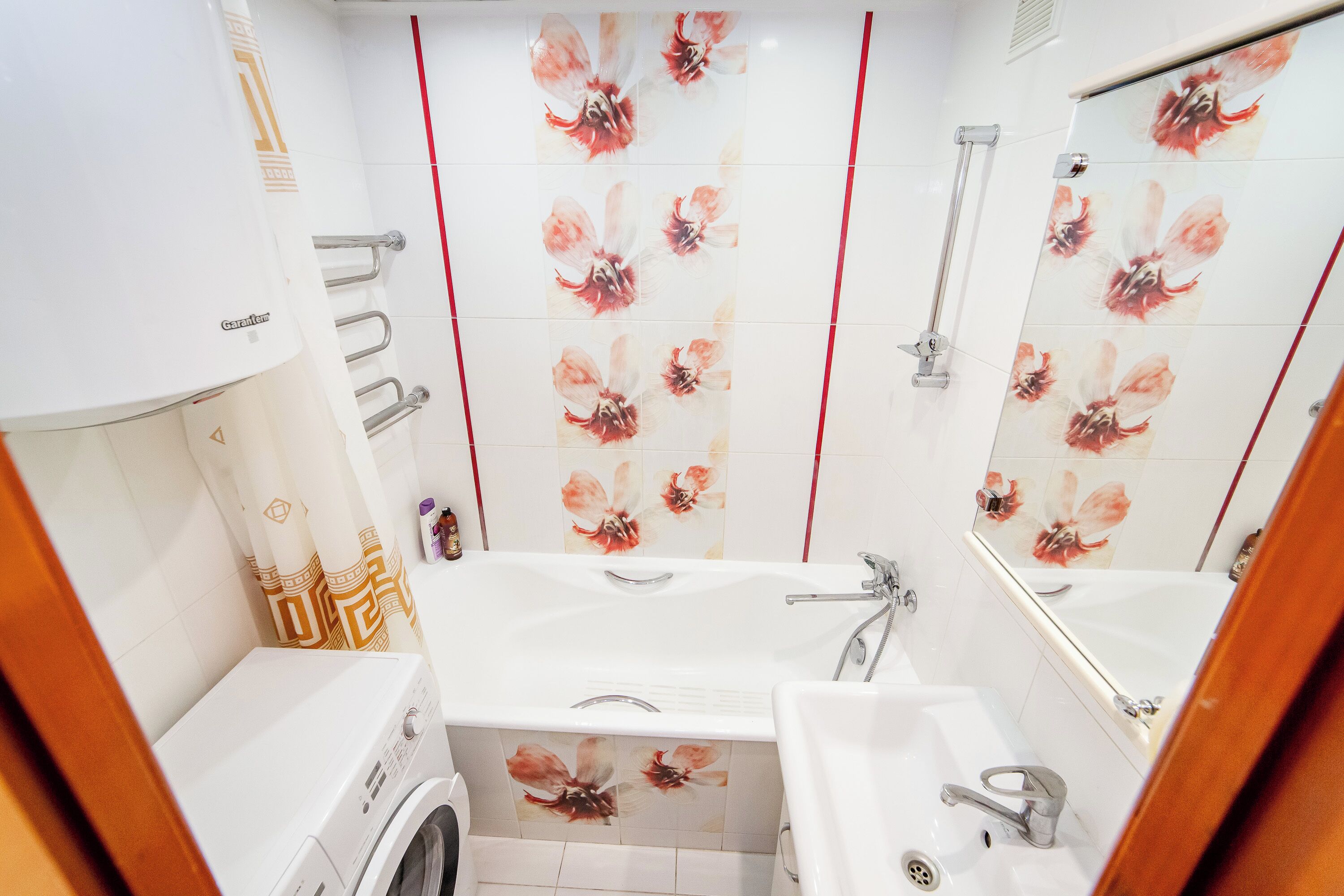 Une salle de bain équipée d’un lave-linge, de deux éviers, d’une baignoire et d’un miroir.