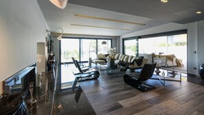 Ampla sala de estar com design moderno, apresentando um sofá grande, uma mesa de centro e uma lareira.