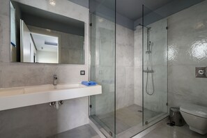 A modern bathroom with a glass-enclosed shower, a white sink with a mirror above it, and a toilet. - Villa Selenia Platinum (Saronikos)
