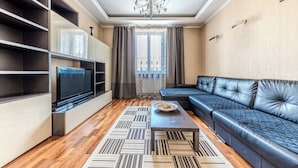 A modern living room with a flat-screen TV, a leather sofa, and a patterned rug. - StudioMinsk Apartments in Centre (Minsk)