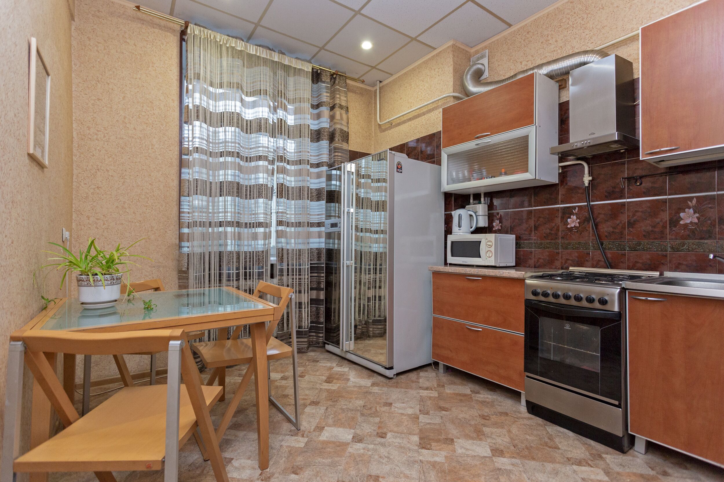 A compact kitchen with a refrigerator, microwave, stove, and wooden cabinets.