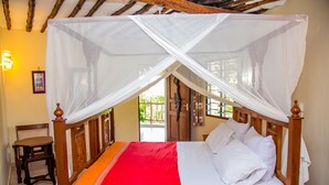 Een bed met baldakijn, een houten stoel en een deur op de achtergrond.