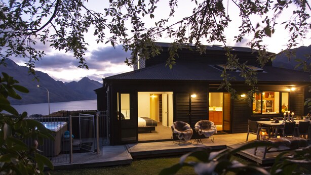 Ein modernes Haus mit Terrasse, Pool und Blick auf Berge und einen See.