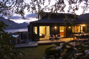 Ein modernes Haus mit Terrasse, Pool und Blick auf Berge und einen See.