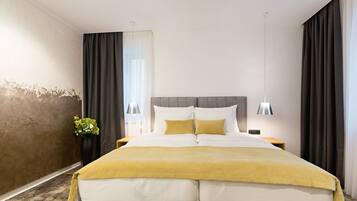 Ett modernt hotellrum med en stor säng, ett sängbord, en lampa och en vas med blommor.
