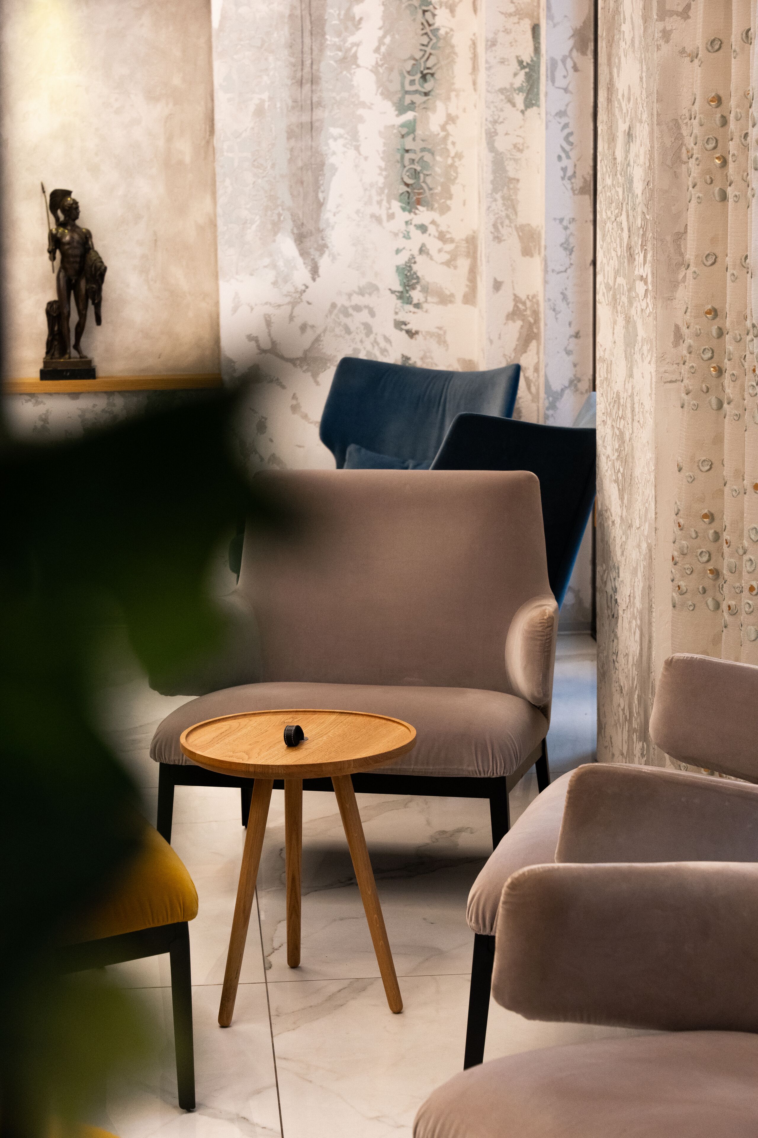 Una sala de estar moderna con un sofá, una mesa redonda de madera y una estatua decorativa en una estantería.