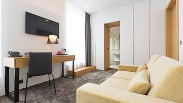 A modern hotel room with a desk, chair, and sofa.