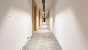 A long, narrow hotel corridor with a carpeted floor and white walls.