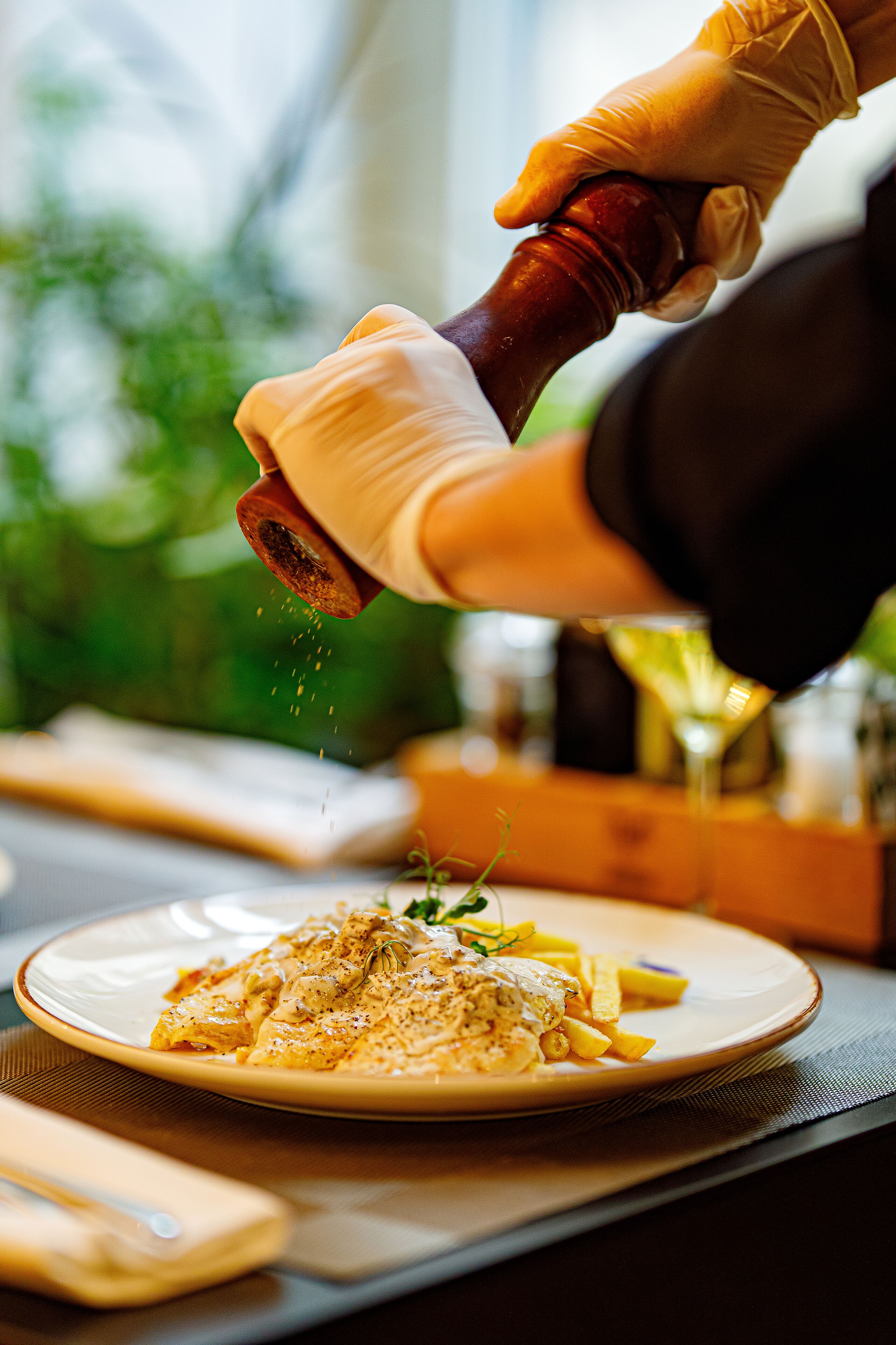 A person seasoning a dish with a pepper grinder.