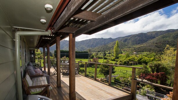 Une terrasse en bois avec des sièges extérieurs et une vue sur un paysage montagneux.