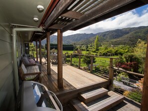 Eine Holzterrasse mit Sitzgelegenheiten und Blick auf eine gebirgige Landschaft.