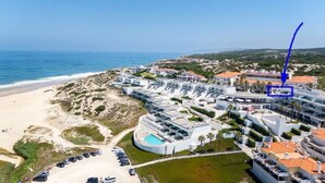 Luftaufnahme eines Küstenhotels mit mehreren Gebäuden, einem Schwimmbad und einem Strand.