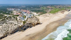 Eine Luftaufnahme einer Küstenstadt mit Strand, Gebäuden und einer Klippe.