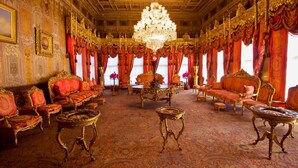 Una sala amplia con muebles elaborados, un candelabro y cortinas rojas.