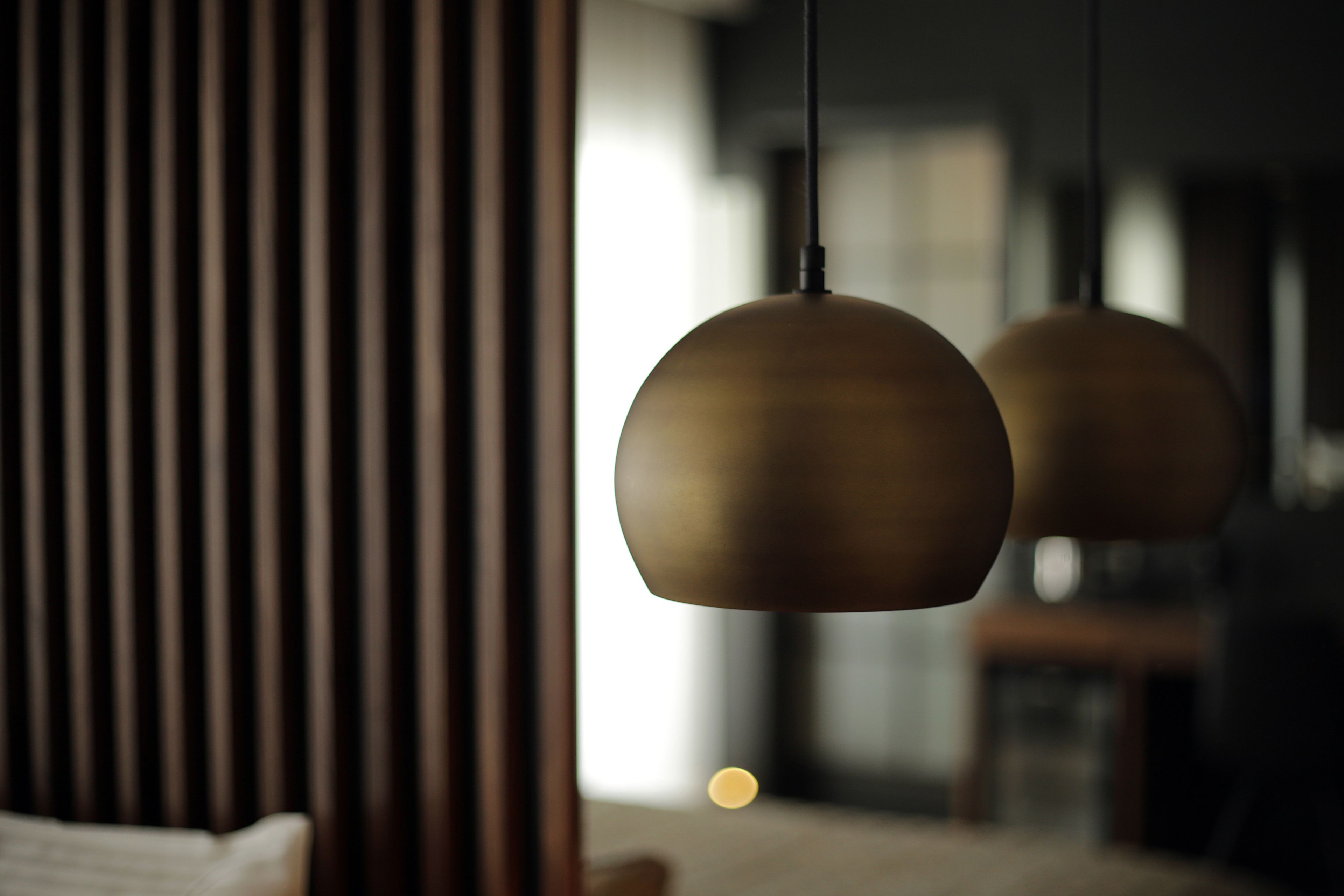 Un interior moderno con un revestimiento de listones de madera y dos lámparas colgantes esféricas.