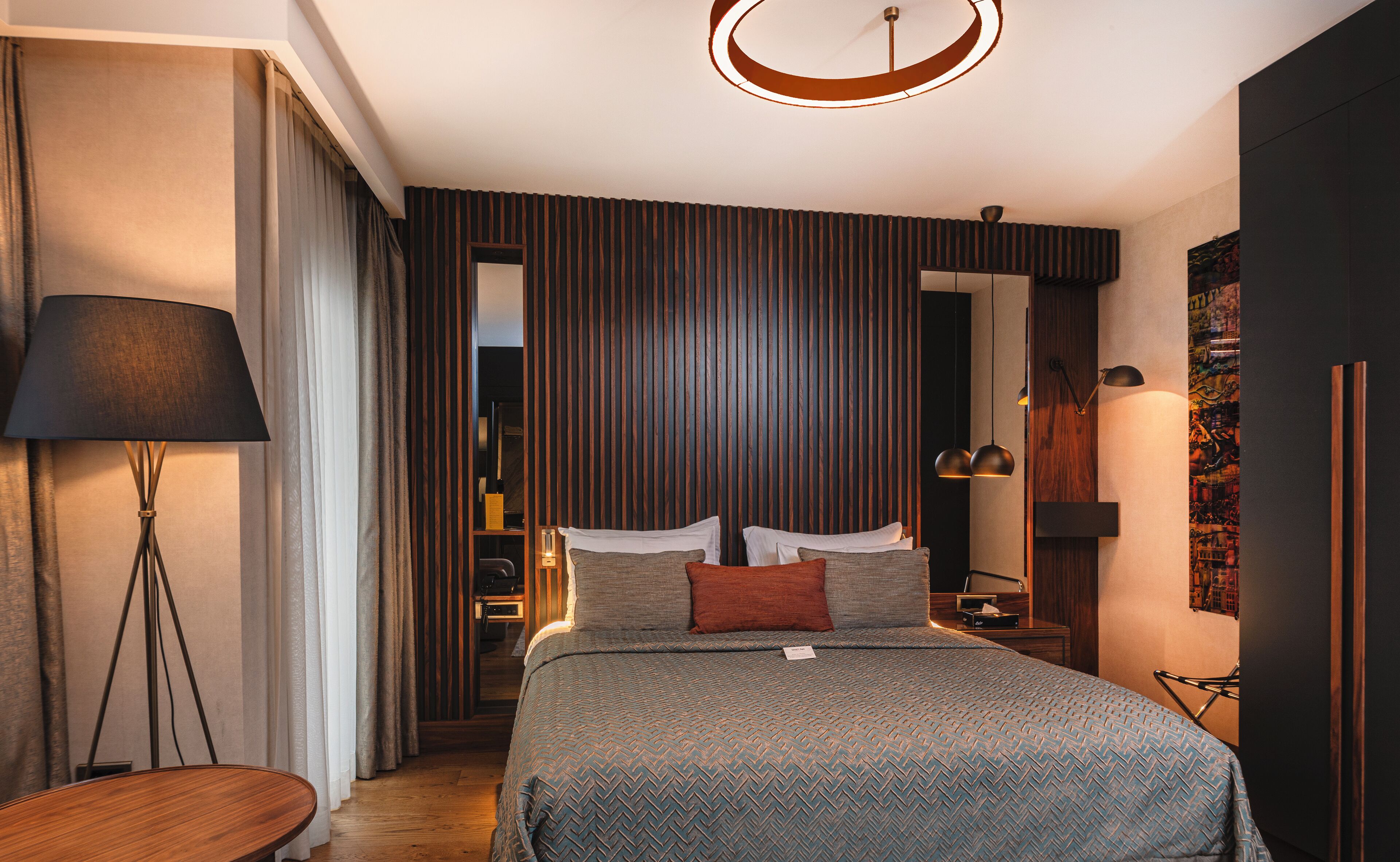 A modern bedroom with a large bed, a bedside table, a floor lamp, and a wardrobe.