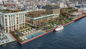 Un hotel frente al agua con bar en la azotea, piscina y muelle para embarcaciones.