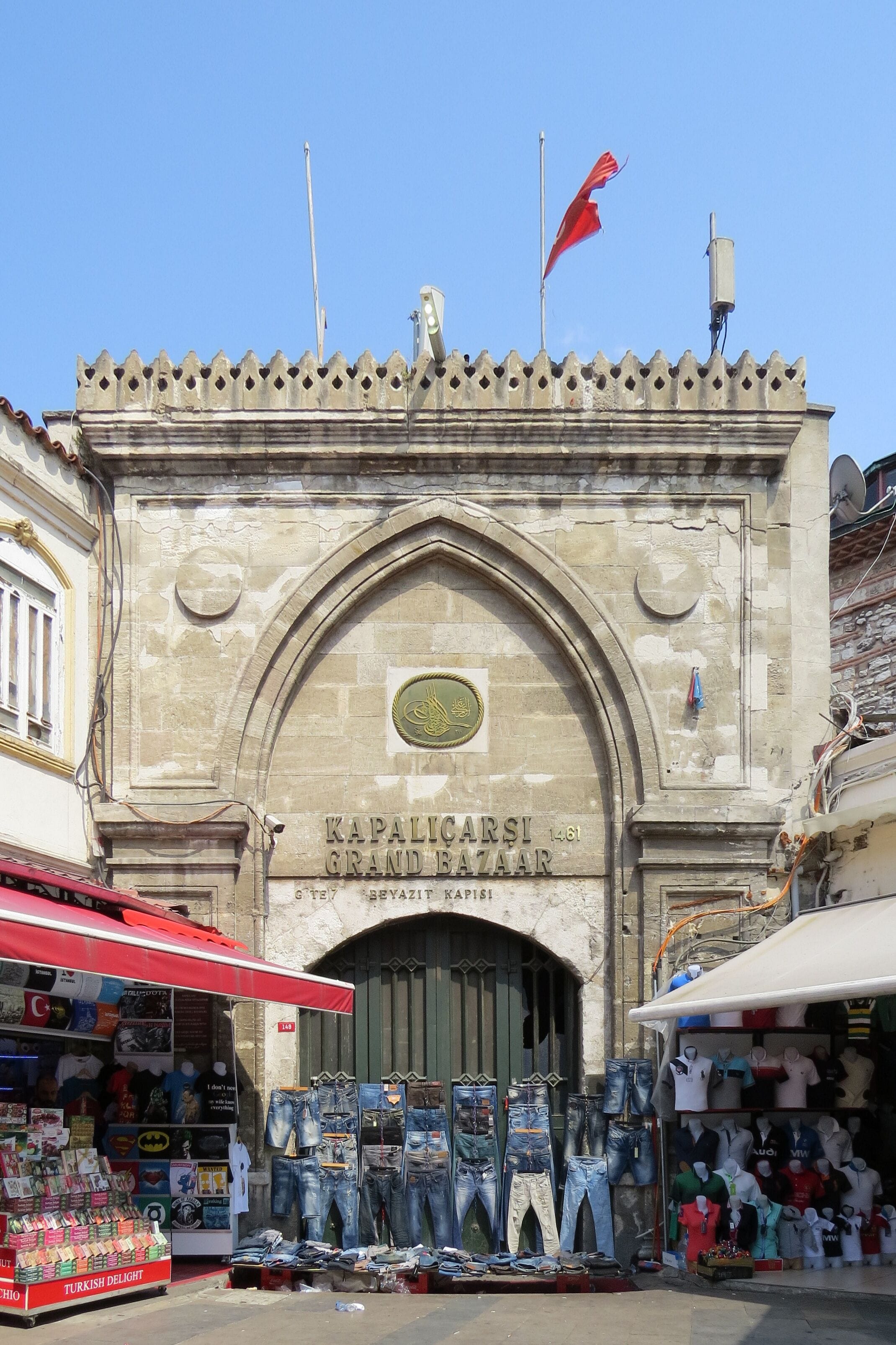 A historic building with a stone facade, a large arched entrance, and a flagpole with a flag.