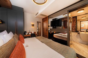 A modern hotel room with a large bed, a desk, a television, and a bathroom with a bathtub. - Levni Plus Hotel (Istanbul)