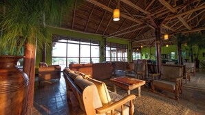 A spacious lobby with wooden furniture, large windows, and a high ceiling.